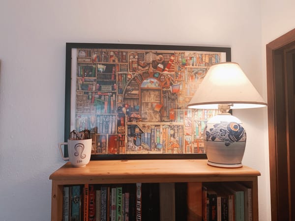 photo of a bookshelf with a fish lamp, a leo mug, and a framed puzzle behind it