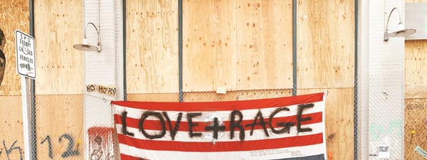 An american flag with graffitti reading "love + rage"